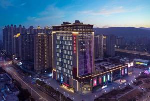 Ramada By Wyndham Xiangyang Xiangcheng في شيانغيانغ: مبنى طويل في مدينة في الليل