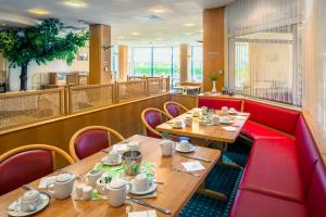 a restaurant with wooden tables and red booths at Akzent Congresshotel Hoyerswerda in Hoyerswerda