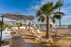 - une plage avec des chaises, des parasols et un palmier dans l'établissement Miami Suite, à Bellaria-Igea Marina