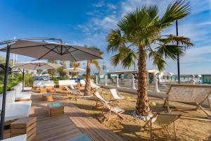 a beach with chairs and umbrellas and a palm tree at Miami Suite in Bellaria-Igea Marina
