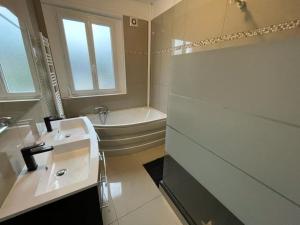 a bathroom with a tub and a sink and a bath tub at Chez F&K in Elbeuf