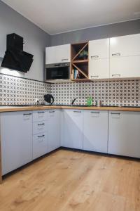 uma cozinha com armários brancos e piso em madeira em Stara Drukarnia - Apartamenty typu Studio em Bydgoszcz