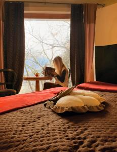 a woman sitting on a bed in front of a window at Villa Amaranta Room and Breakfast in Edolo