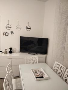 a white dining room with a table and a tv at VerdeMare in Montesilvano