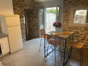 eine Küche mit einem Tisch und Stühlen sowie einem Kühlschrank in der Unterkunft Charmant logement in Rogliano