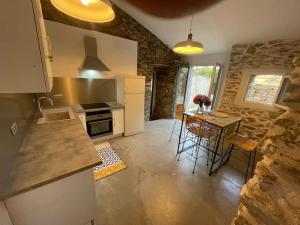 a kitchen with a counter and a table with chairs at Charmant logement in Rogliano