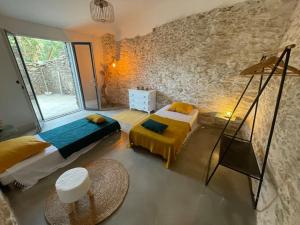 a bedroom with two beds and a stone wall at Charmant logement in Rogliano +19 photos