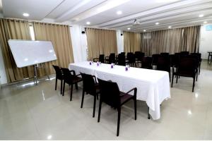 una sala de conferencias con una mesa blanca y sillas negras en Hotel Girnar, en Aurangabad
