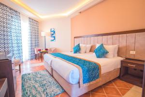 a bedroom with a large bed with blue pillows at Ivy Cyrene Sharm Resort Adults Friendly Plus 13 in Sharm El Sheikh
