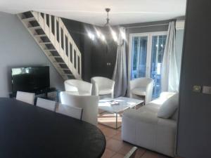 a living room with white furniture and a staircase at Les Jasmins 8 pers Piscine commune calme et confort in Saint-Gilles