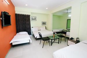 Habitación de hotel con 2 camas y mesa en Hotel Shree, en Indore