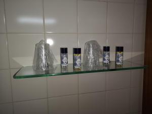 a glass shelf on a white tiled wall with bottles on it at Hotel Santa Comba in Moura