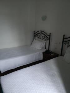 a bedroom with two beds and a night stand with a bedskirts at Hotel Santa Comba in Moura