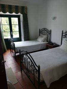 two beds in a room with a window at Hotel Santa Comba in Moura