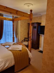 a bedroom with a canopy bed and a television at St Vincent Guest House in Lynton