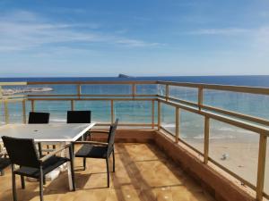 Un balcón con mesa y sillas y el mar. en Ático Primera Línea Parque de Elche, en Benidorm