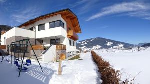 ein Gebäude im Schnee mit einem Basketballkorb in der Unterkunft Haus Lienbacher in Flachau
