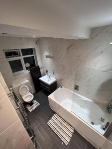 a bathroom with a tub and a toilet and a sink at 5- bed gem in Barnet short let luxury awaits in Barnet