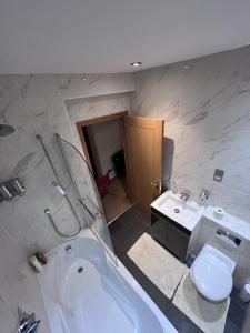 a bathroom with a tub and a toilet and a sink at 5- bed gem in Barnet short let luxury awaits in Barnet