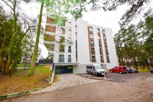 un edificio bianco con un'auto parcheggiata in un parcheggio di Apartament Leśny No 63 nad Zalewem z KOMINKIEM , GARAŻ w cenie a Kielce