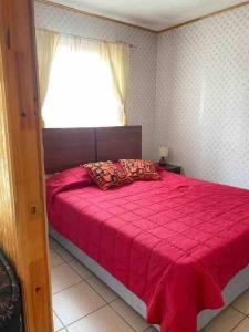 Schlafzimmer mit einem großen roten Bett und einem Fenster in der Unterkunft Cabañas Pino, Un lindo lugar de descanso -playa I in Las Cruces