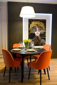 tavolo da pranzo con sedie arancioni e dipinto di una donna di Apartament Leśny No 63 nad Zalewem z KOMINKIEM , GARAŻ w cenie a Kielce