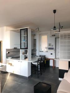 a kitchen with white cabinets and a table with chairs at Appartamento vista lago Le Terrazze piscina-tennis-parking in Menaggio