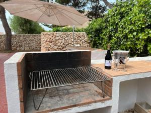 tavolo da picnic con una bottiglia di vino e un ombrello di Lulu Menorca Modern apartment 300m from Cala Blanca beach a Cala Blanca