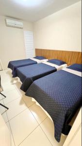three beds in a room with blue comforters at Avelan Plaza Hotel in Nossa Senhora da Glória