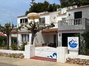 una casa bianca con un albero davanti di Lulu Menorca Modern apartment 300m from Cala Blanca beach a Cala Blanca