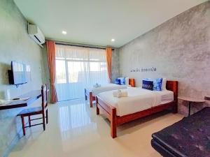 a hotel room with two beds and a desk at Hug Sakhonnakhon Hotel in Sakon Nakhon