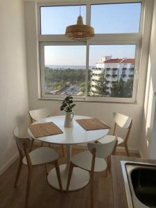 un tavolo bianco con sedie in una stanza con finestra di Apartamento T2 Montegordo a 500 m da praia a Monte Gordo