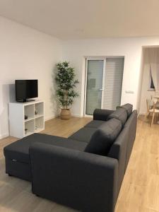 uma sala de estar com um sofá preto e uma televisão em Apartamento T2 Montegordo a 500 m da praia em Monte Gordo