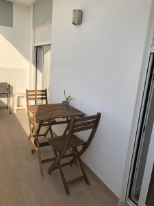 a wooden table and chairs next to a white wall at Apartamento T2 Montegordo a 500 m da praia in Monte Gordo