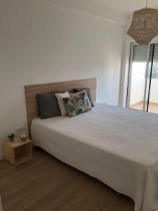 a bedroom with a large white bed and a window at Apartamento T2 Montegordo a 500 m da praia in Monte Gordo