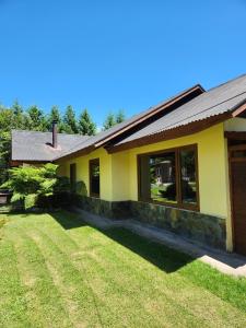 a yellow house with a lawn in front of it at Casa Campestre con piscina compartida in Villarrica