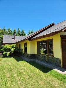 una casa amarilla con césped delante en Casa Campestre con piscina compartida, en Villarrica