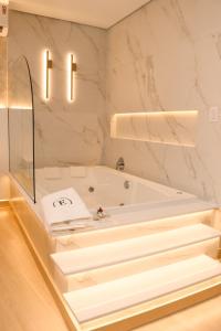 baño con bañera blanca y paredes de mármol en Estação Termas Hotel, en Piratuba