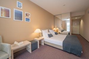 um quarto com uma cama, um sofá e uma cadeira em Hotel Zlatna Vala em Umago