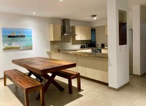 una cocina con mesa de madera y bancos. en Moringa Gardens Self Catering Apartments en Swakopmund