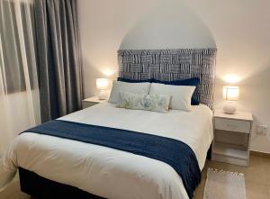 een slaapkamer met een groot wit bed met 2 lampen bij Moringa Gardens Self Catering Apartments in Swakopmund