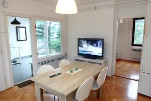 een eetkamer met een houten tafel en een televisie bij Warm and Comfy Piran Apartment with Parking! in Piran