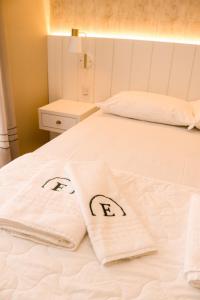 Una cama blanca con dos toallas encima. en Estação Termas Hotel, en Piratuba