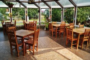 ein Restaurant mit Holztischen, Stühlen und Fenstern in der Unterkunft Domki "Berenika" in Rewal