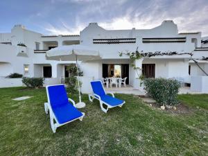 twee blauwe stoelen en een paraplu voor een huis bij Albufeira Balaia Golf Village 1 With Pool by Homing in Albufeira