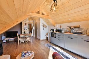a kitchen and living room with a wooden ceiling at Au chalet de JO avec accès à l'espace piscine et jacuzzi in Muhlbach-sur-Munster