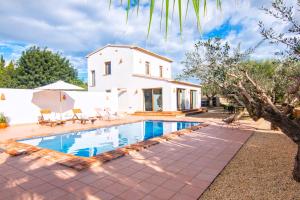 a villa with a swimming pool in front of a house at Finca Les Oliveres in Benissa