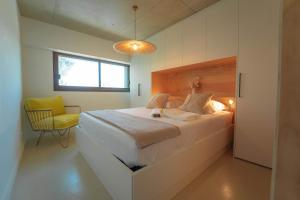 1 dormitorio con 1 cama grande y 1 silla amarilla en Villa Ananda - Surya - un havre de paix avec vue mer et étangs, en Carnon-Plage