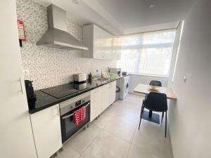 a kitchen with a stove and a sink and a table at Central Station Apartment in Setúbal