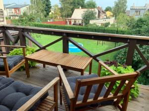 a wooden deck with chairs and a table and a pool at Nicas guest house in Liepāja